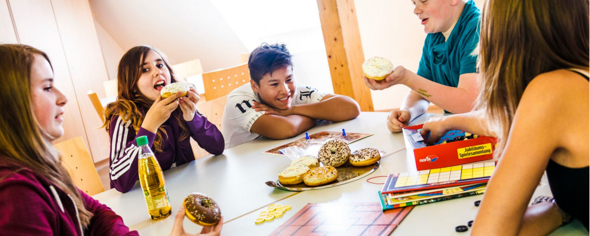 Jugendliche beim Donut essen und Gesellschaftsspiele spielen