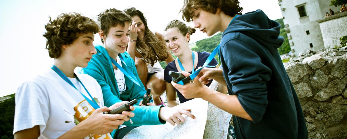 Eine Gruppe Jugendlicher orientiert sich mit Hilfe von Karte und GPS Geräten