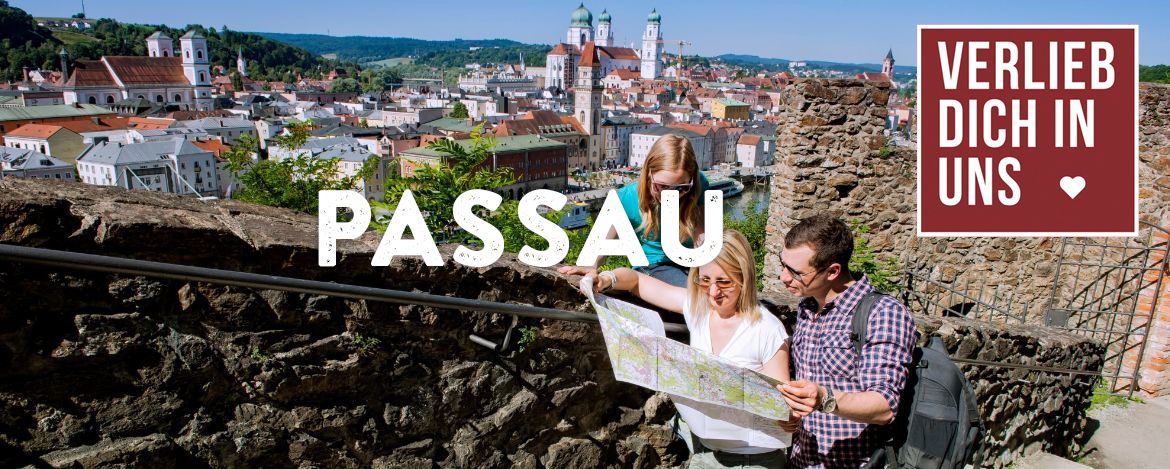 Blick über die Häuserdächer, im Vordergrund zwei Menschen mit einer Landkarte. Das Foto wird überlagert von den Schriftzügen "Verlieb dich in uns" und "Passau"