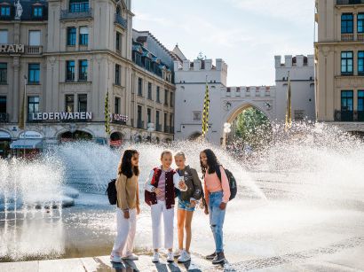 Jugendlichen stehen vor dem Springbrunnen am Karlsplatz in München