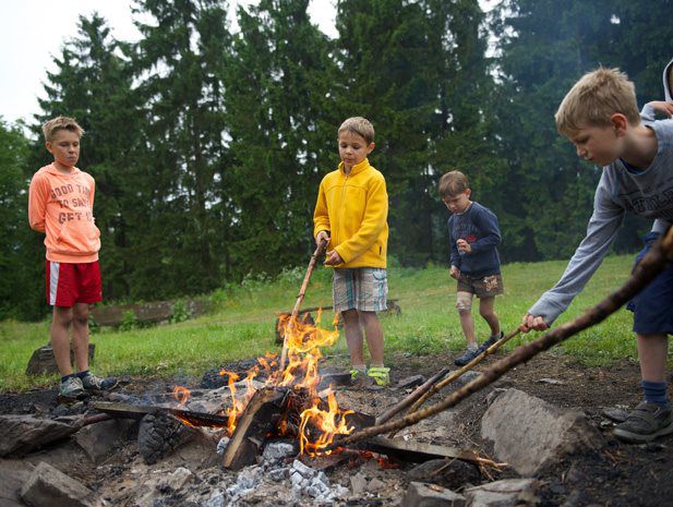 LAGERFEUERROMANTIK - Die große Feuerstelle ist das Zentrum des Familienlagers. Gleich hinter dem Lager beginnt der Wald. Immer wieder klettern die Kinder den Hang hinab, um Feuerholz oder Stöcke zum Schnitzen zu sammeln.