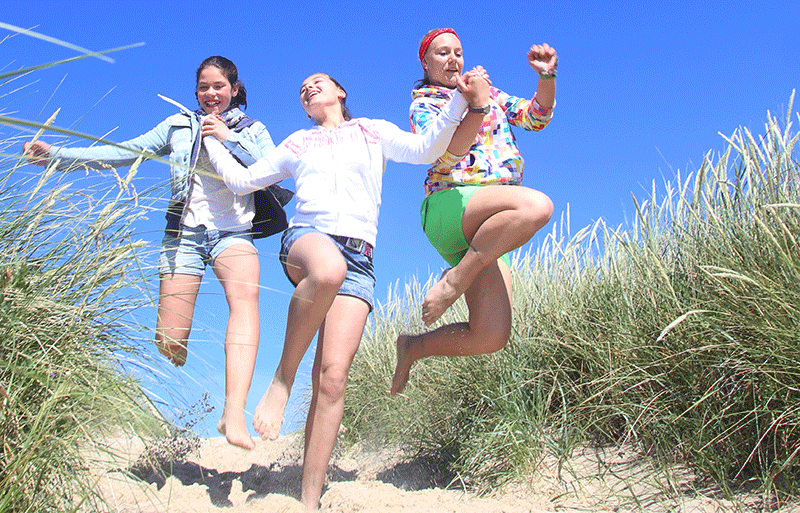 Drei Mädchen springen in den Dünen im Urlaub auf Sylt
