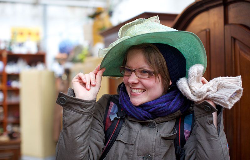 Junge Frau probiert einen Hut beim Kurztrip mit den Freundinnen