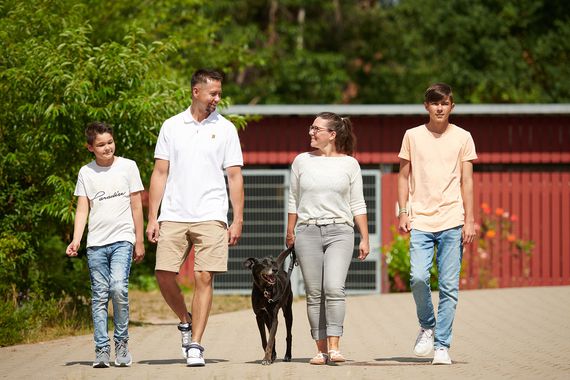 Vater, Mutter und zwei Kinder auf einem Spaziergang im Familienurlaub mit Hund. 