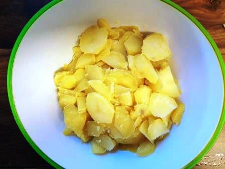 Noch warme, gepellte Kartoffeln in Scheiben schneiden 