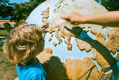 Ein Kind schaut sich auf einer übermannshohen Weltkugel Europa an.