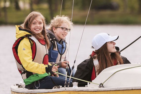 Drei Schülerinnen sitzen in einem Segelboot. 
