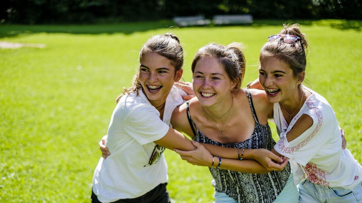 Drei junge Frauen umarmen sich lachend