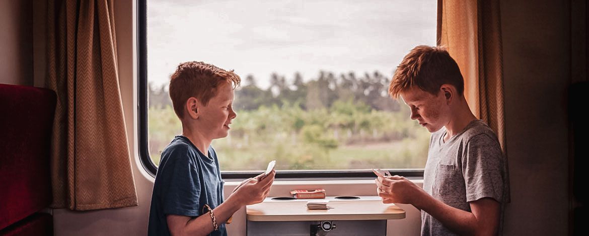 Zwei Jungs sitzen im Zug und spielen Karten