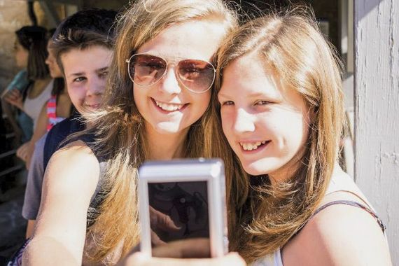 Zwei junge Frauen blicken in die Kamera und machen dabei ein Selfie von sich
