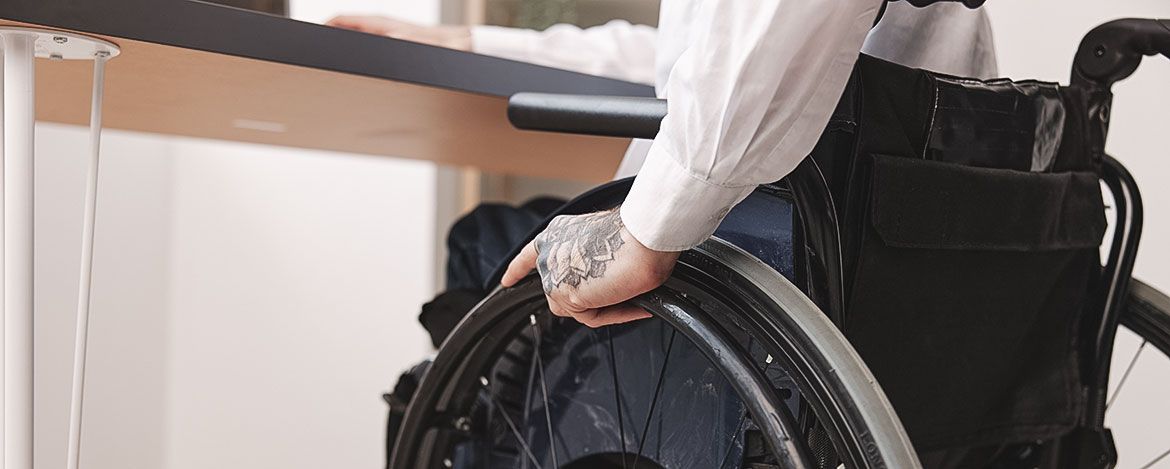Ein Rollstuhlfahrer an seinem Arbeitsplatz im Seminarraum