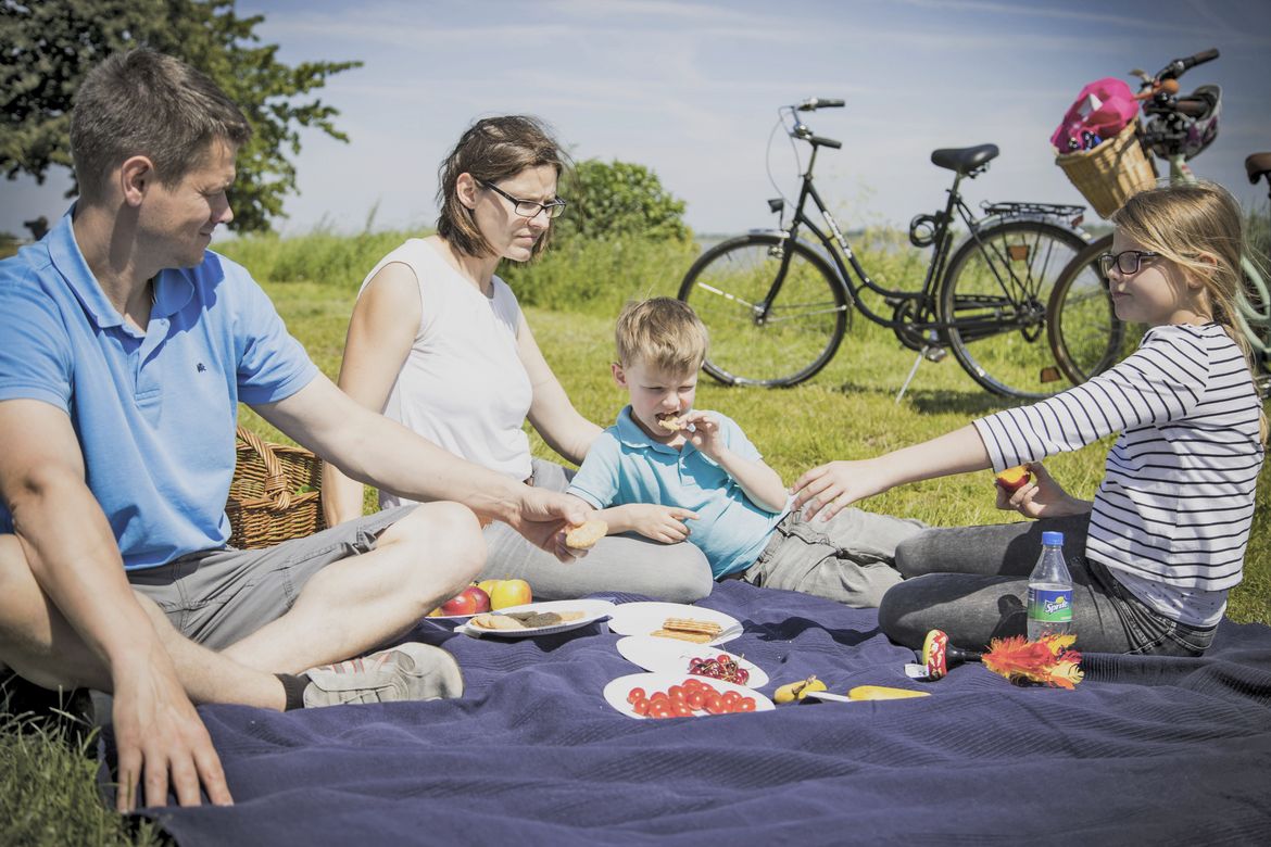 Eine Familie mit Fahrrädern stärkt sich mit einem Lunchpaket