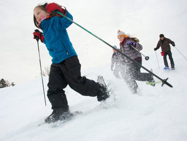 Kinder stapfen mit Schneeschuhen durch tiefen Schnee