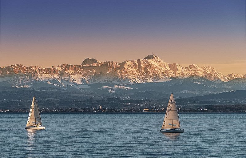 Bodensee mit Segelschiffen und Bergen im Hintergrund