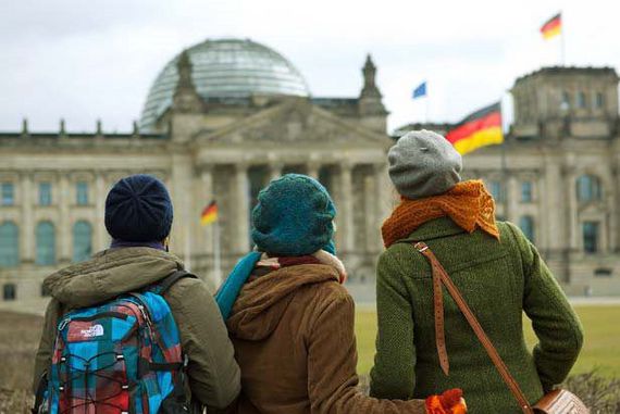 Drei junge Frauen stehen mit dem Rücken zur Kamera vor dem Reichstagsgebäude.