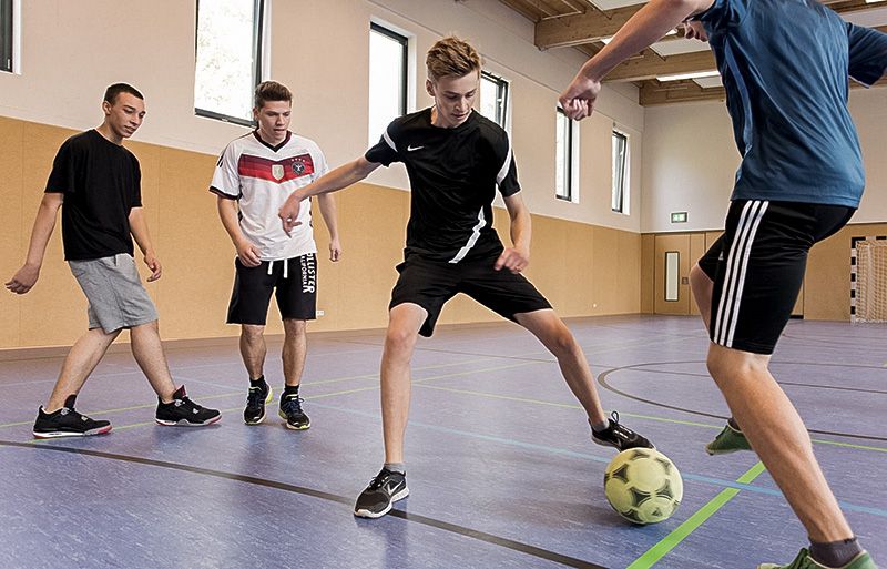 Jungs spielen Fußball in einer Sporthalle