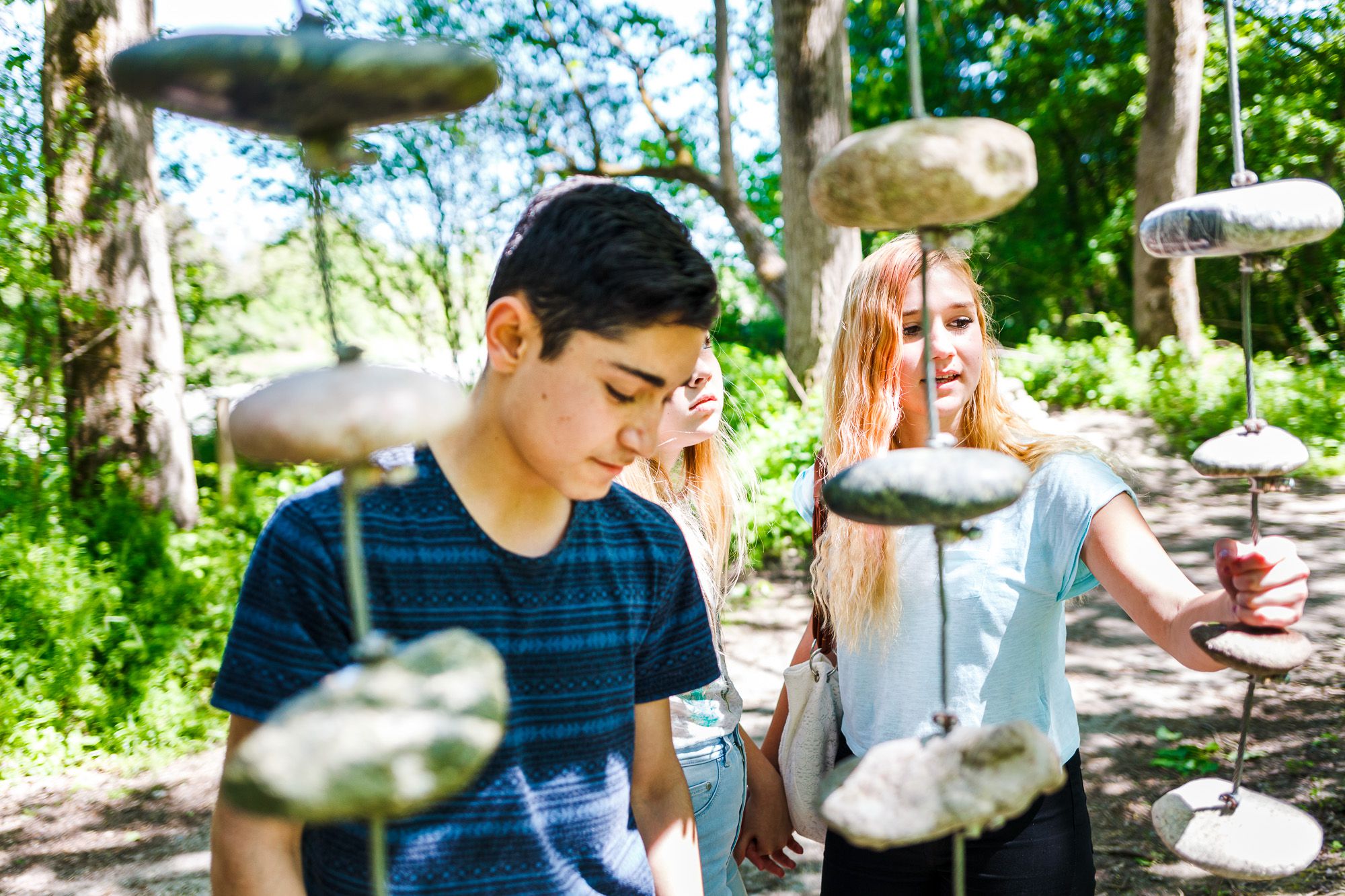 Drei Schüler experimentieren mit Steinen, die auf senkrechten Metallstangen befestigt sind.