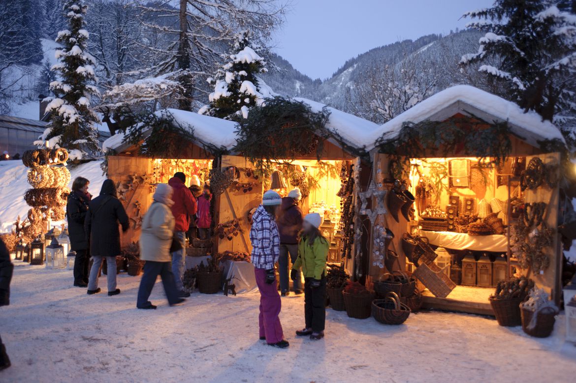 Christkindlmarkt in einer verschneiten Landschaft mit Bergen im Hintergrund