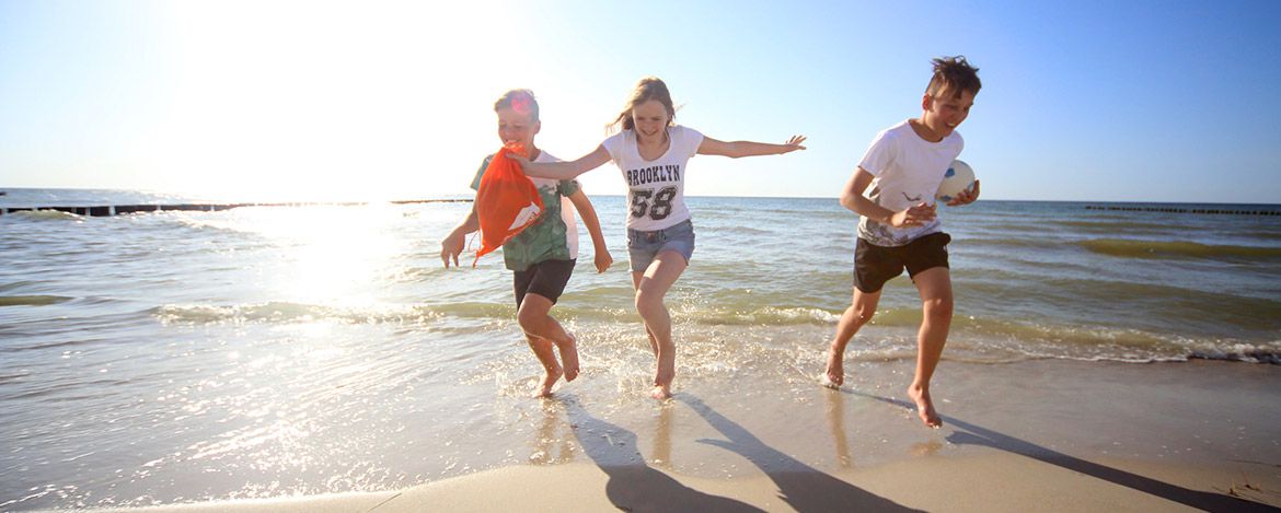 Kinder rennen am Strand im Familienurlaub