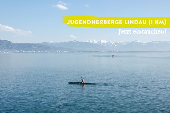 Weiter Block über den Bodensee. Im Zentrum des Fotos ein Kajak auf dem See. Das Bild wird überlagert vom Schriftzug "Jugendherberge Lindau - jetzt eintauchen".