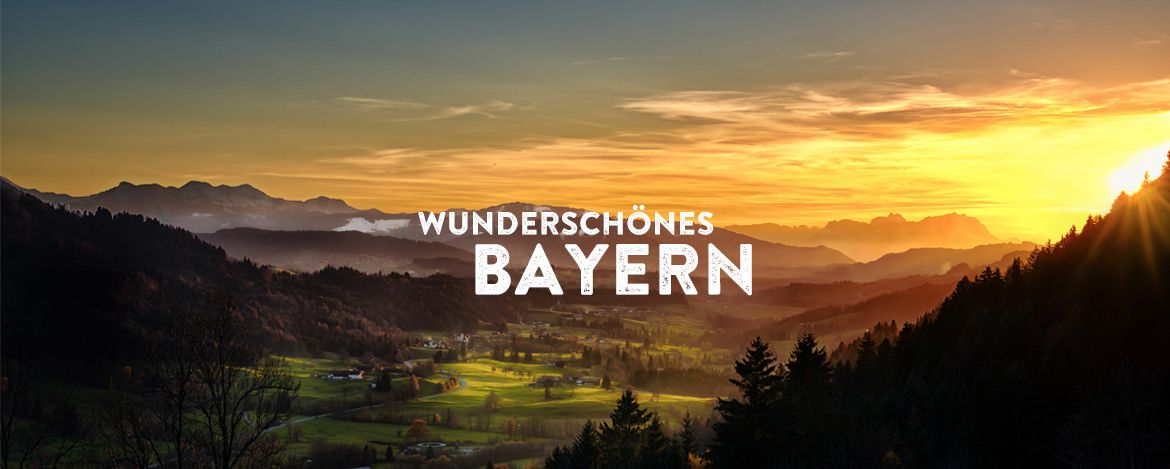 Eine hügelige Landschaft mit Wiesen, Wäldern und Bergen im Sonnenuntergang. Das Foto wird überlagert von dem Text "Wunderschönes Bayern".