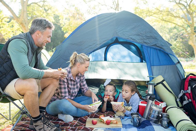 Eine Familie picknickt vor einem Zelt