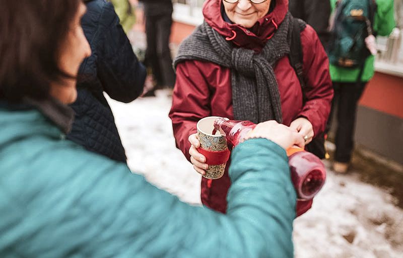 Eine Person gießt einer anderen ein Getränk ein beim Fastenwandern im Harz 