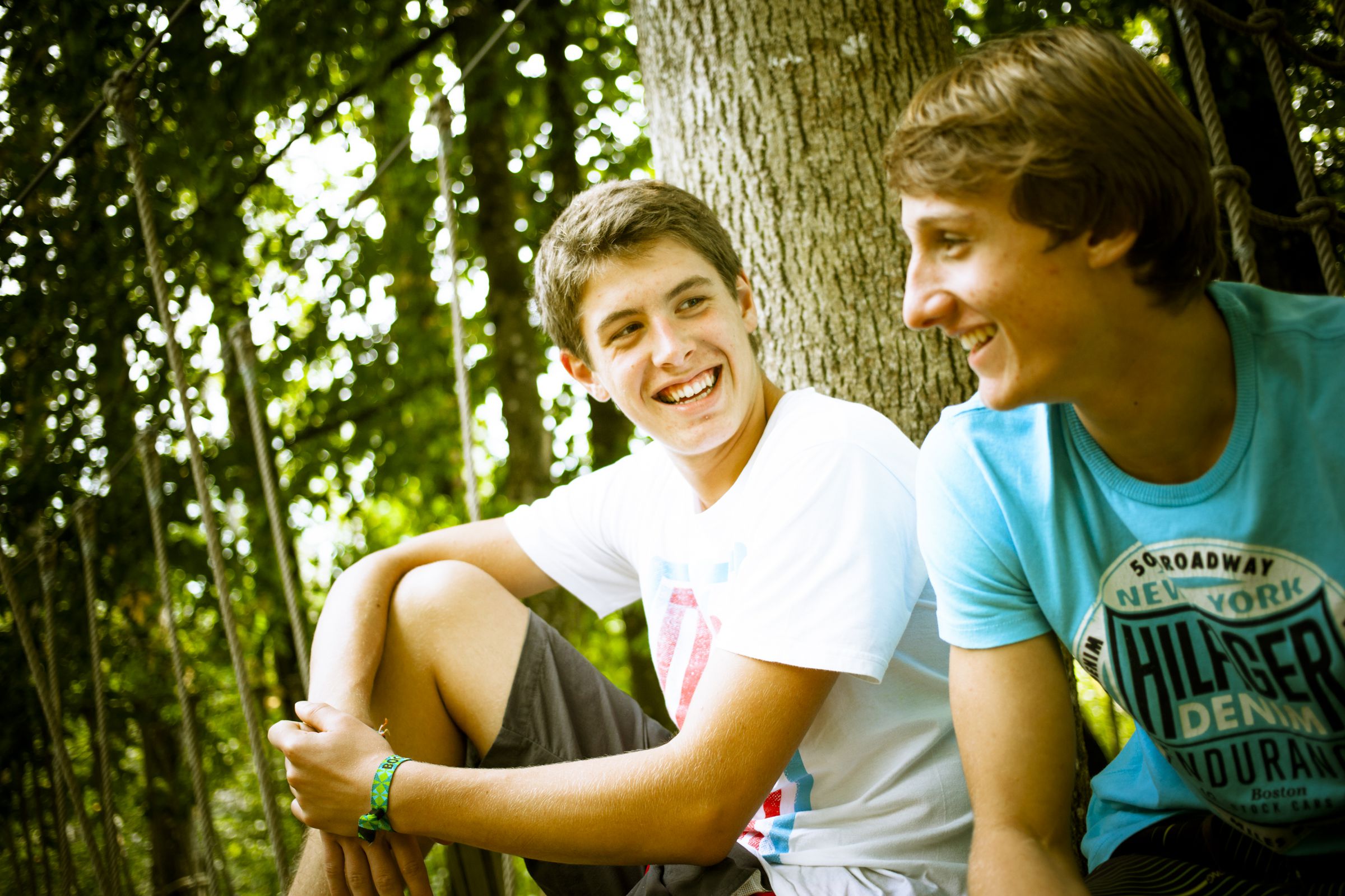 Zwei junge Männer sitzen im Wald und blicken sich an.