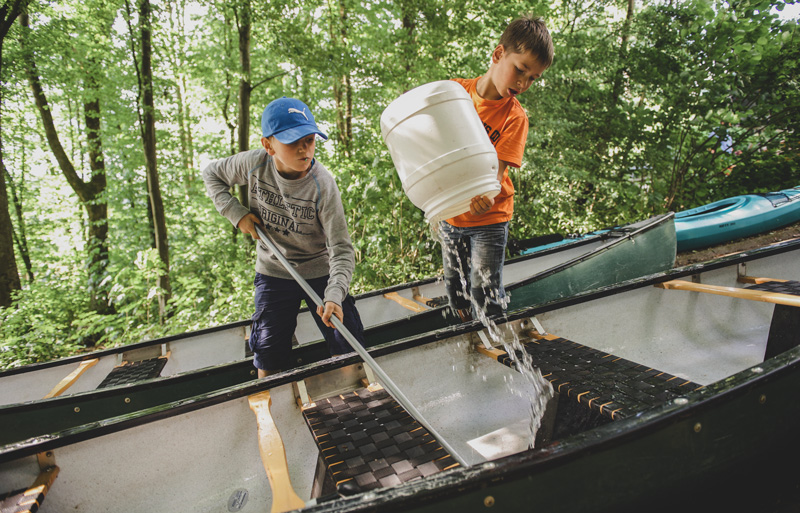 Zwei Jungs machen ein Kanu sauber