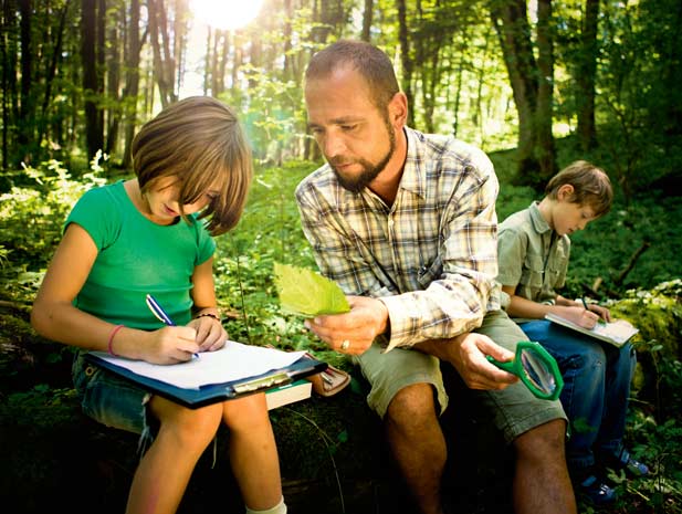 Mann und Kind sitzen auf Baumstamm im Wald 