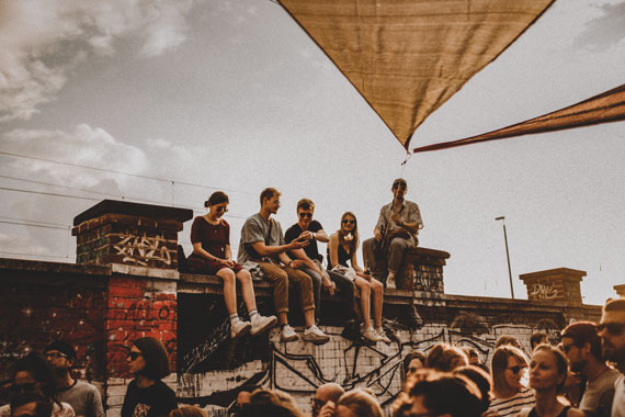 Junge Menschen sitzen bei Ihrer Abschluzssfahrt auf einer Mauer in München