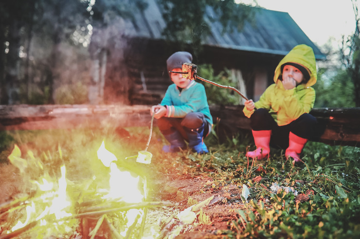 Little children frying marshmallows on bonfire at night. Summer camp