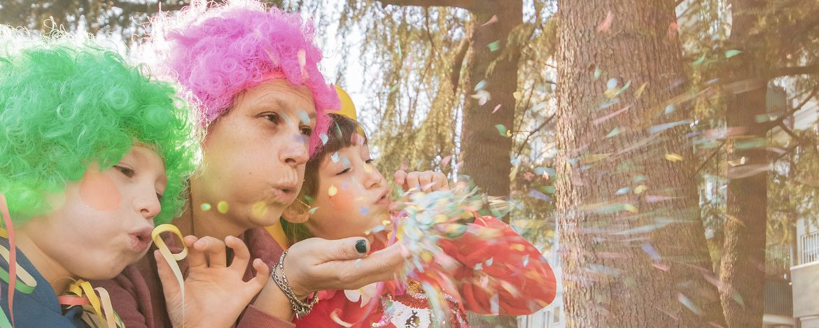 a mother and her children are playing with confetti in carnival costume