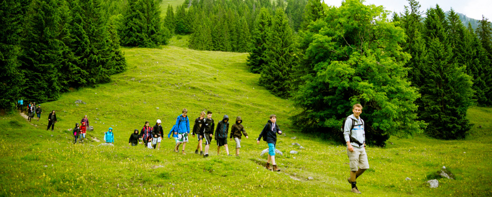 Junge Menschen wandern mit einem Guide durch die Berglandschaft