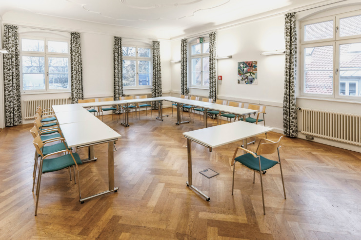 Der Seminarraum Lindau in der Jugendherberge Lindau ist ausgestattet mit Tischen und Stühlen in U-Form, Schreibwänden, Bilder an den Wänden und viel Helligkeit.