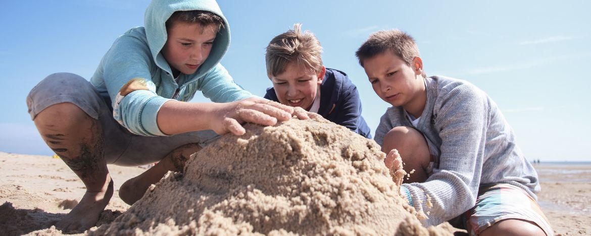 Sandburgenbau am Strand auf Klassenfahrt