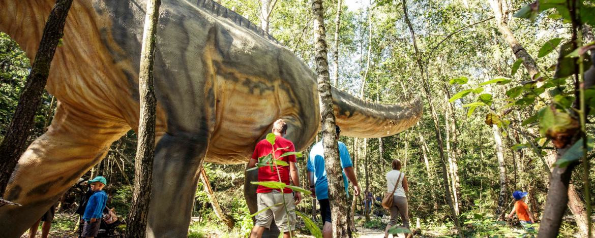 Menschen erkunden lebensgroße Dinosaurier im Dinopark Denkendorf