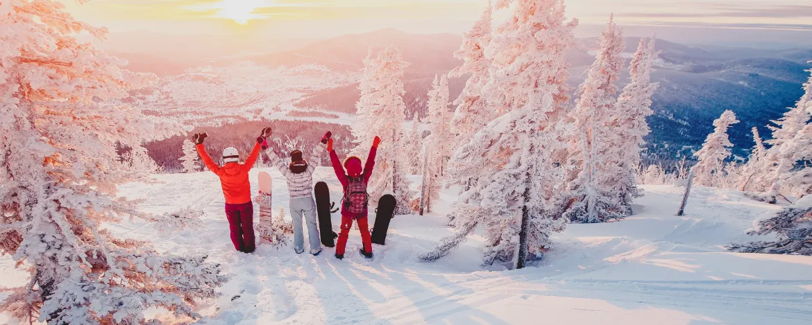 Group of snowboarders friends meet the dawn in mountains. They raised their arms up, they were happy, they were having fun. Concept friendship, rest in winter