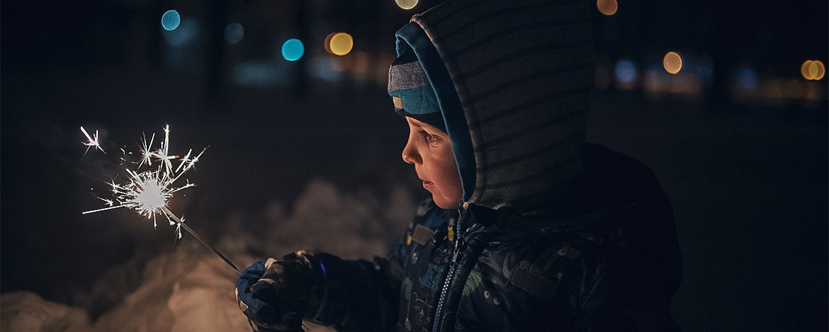 boy holds a sparkler in his hands while celebrating a new year on the street at night.